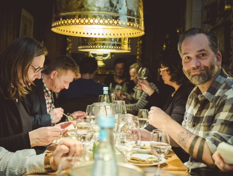 Eine Gruppe von Menschen sitzt mit Weingläsern an einem Tisch.