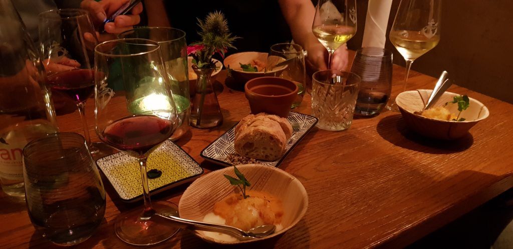 Eine Gruppe von Menschen sitzt an einem Tisch mit Wein und Essen.