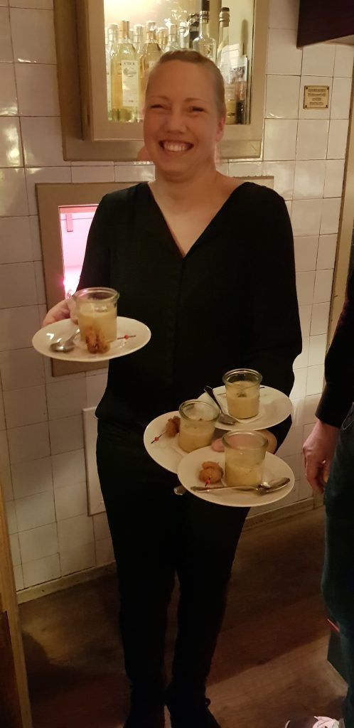 Eine Frau hält vier Teller mit Nachtisch in einem Restaurant.
