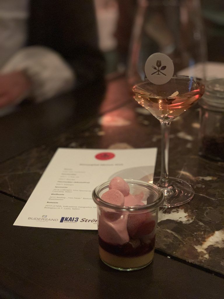 Ein Glas Wein und ein Dessert auf einem Tisch.