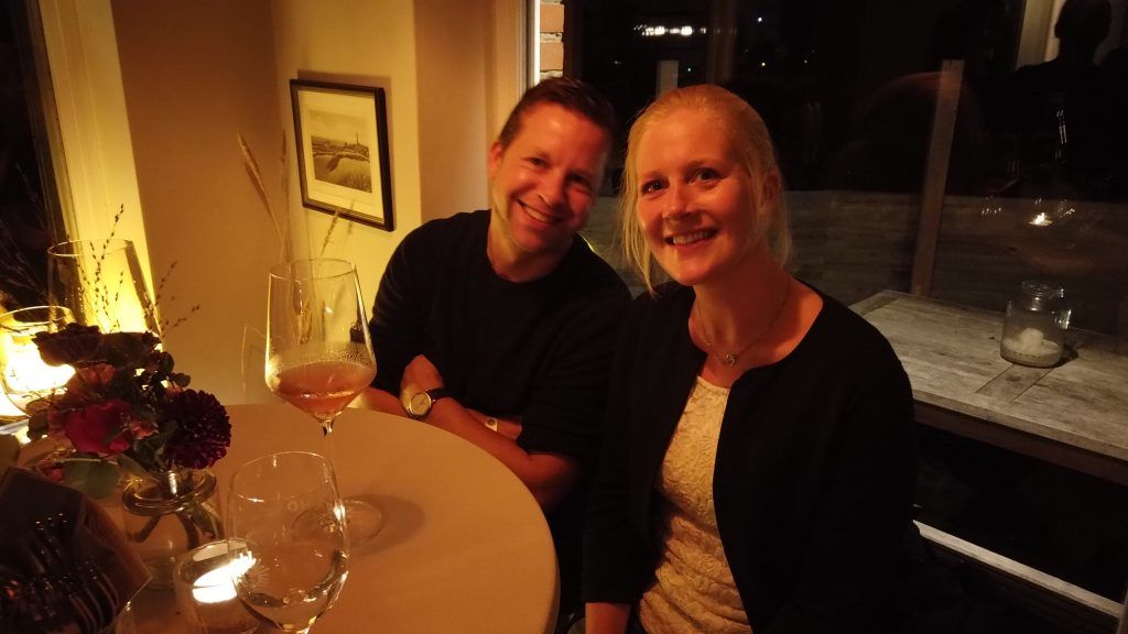 Ein Mann und eine Frau sitzen mit Weingläsern an einem Tisch.