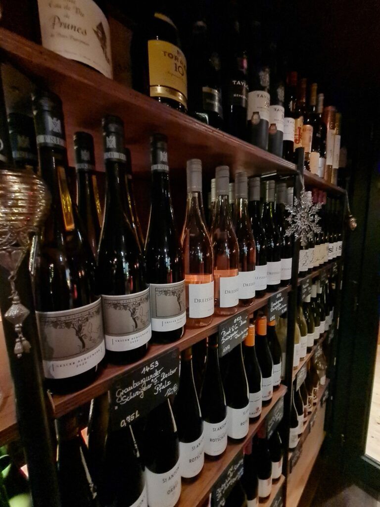 Auf einem Regal stehen viele Flaschen Wein aufgereiht.