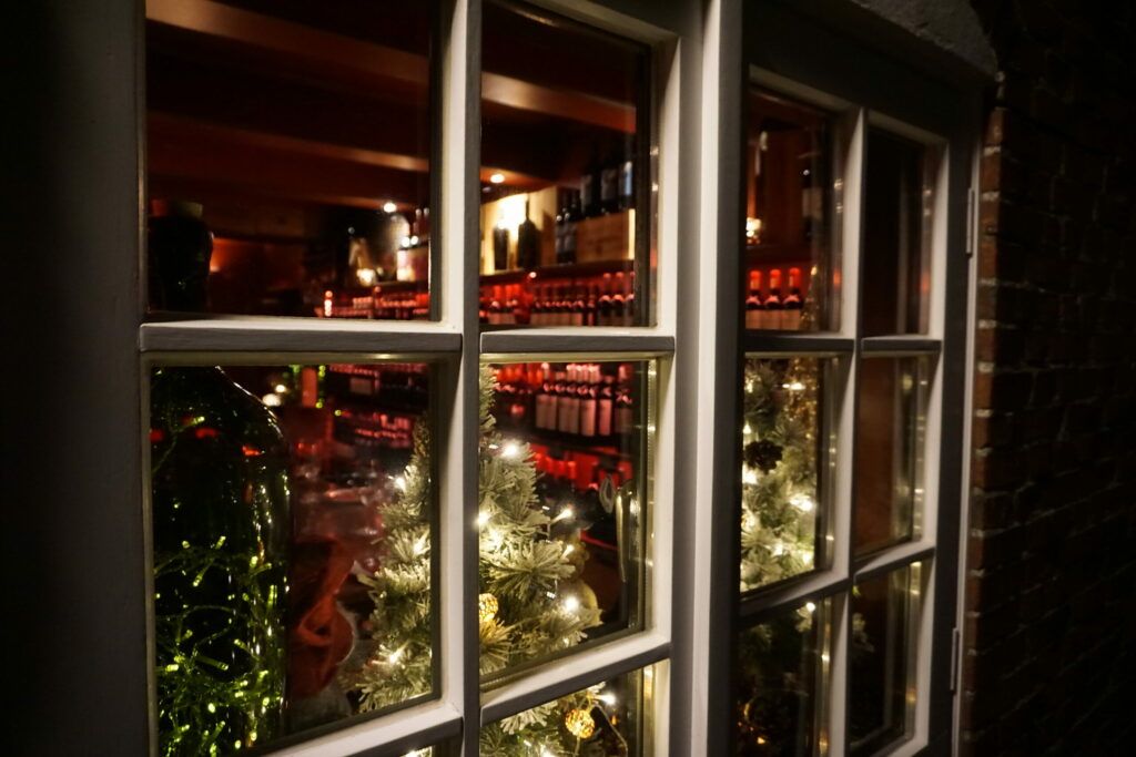 Ein Fenster mit einem Weihnachtsbaum und Weinflaschen.