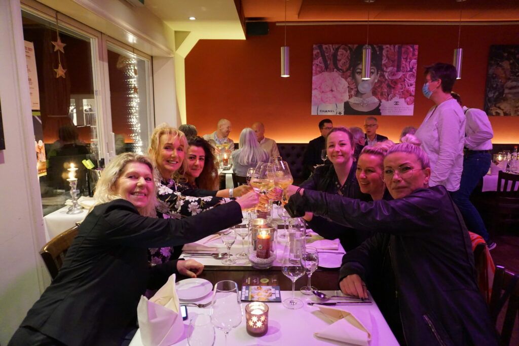 Eine Gruppe von Frauen prostet an einem Tisch in einem Restaurant zu.