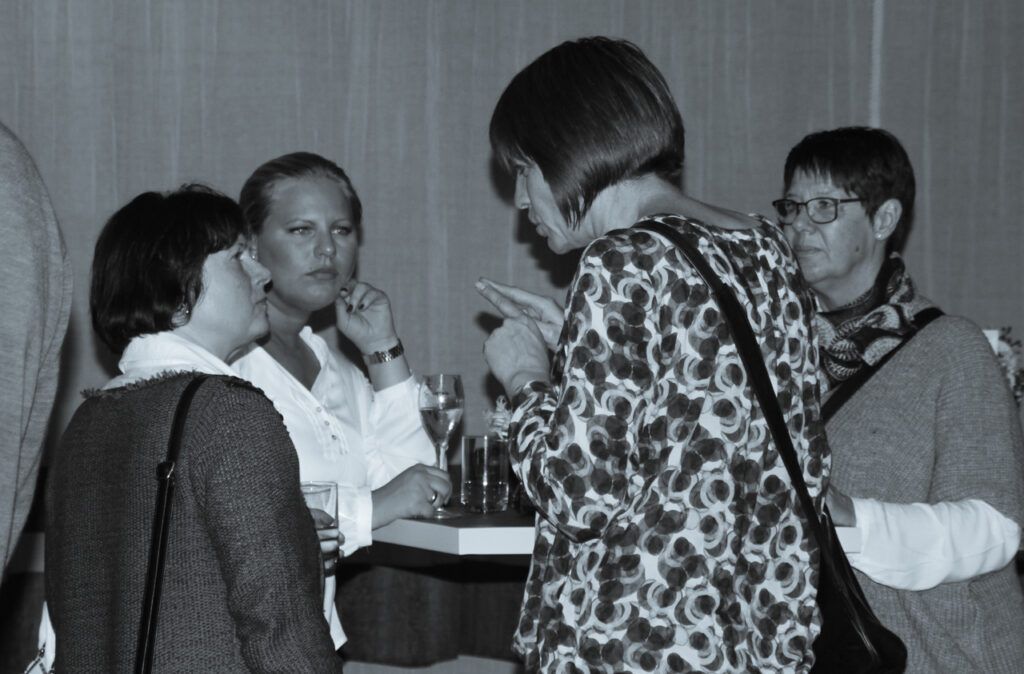 Eine Gruppe von Menschen, die auf einem Schwarz-Weiß-Foto miteinander reden.