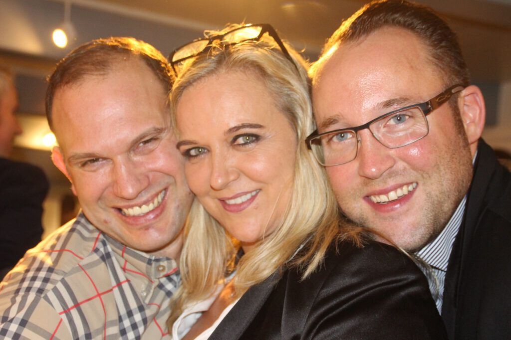Drei Personen posieren für ein Foto auf einer Party.