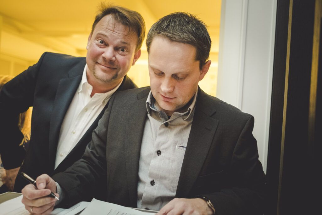 Zwei Männer unterzeichnen vor einem Tisch ein Dokument.