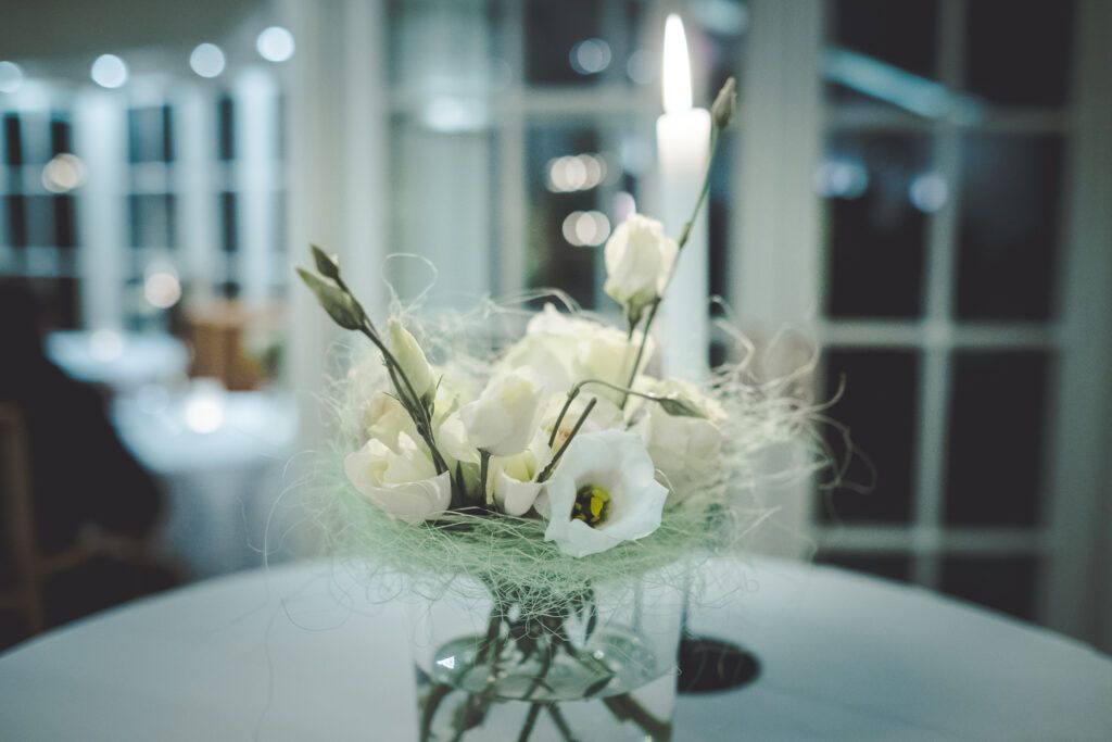Weiße Blumen in einer Glasvase auf einem Tisch.