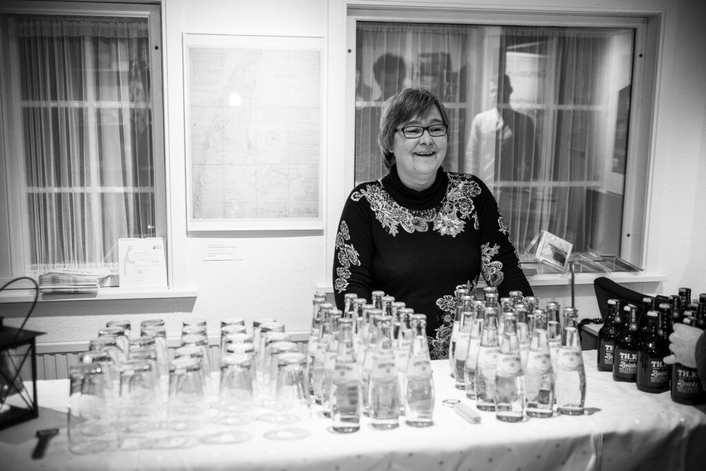 Eine Frau steht vor einem Tisch voller Flaschen.