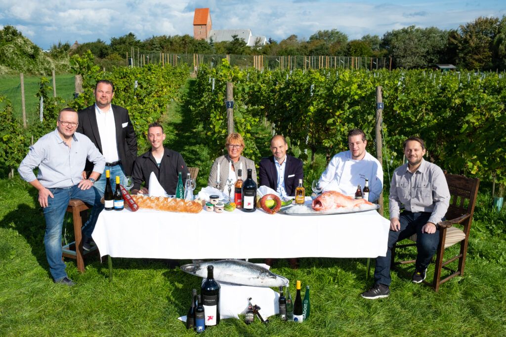 Eine Gruppe von Menschen posiert für ein Foto vor einem Tisch voller Wein.