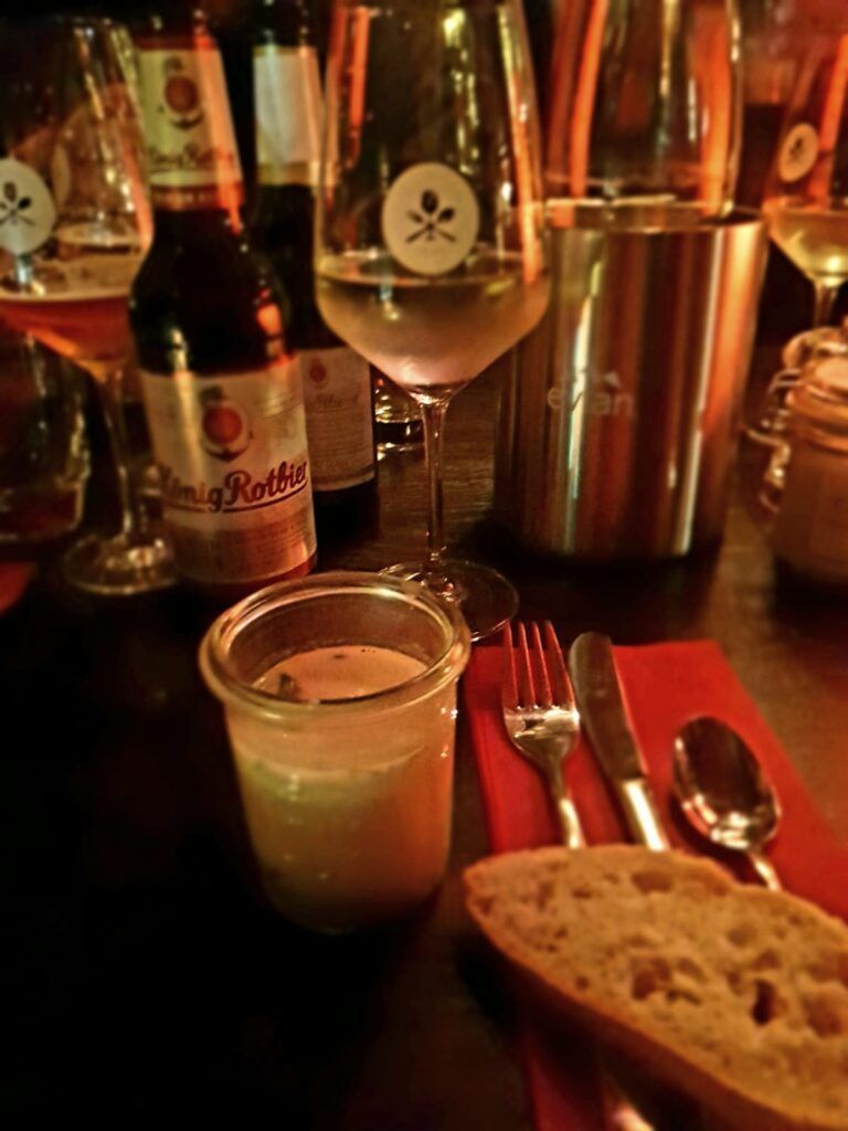 Ein Glas Bier und Brot auf einem Tisch.