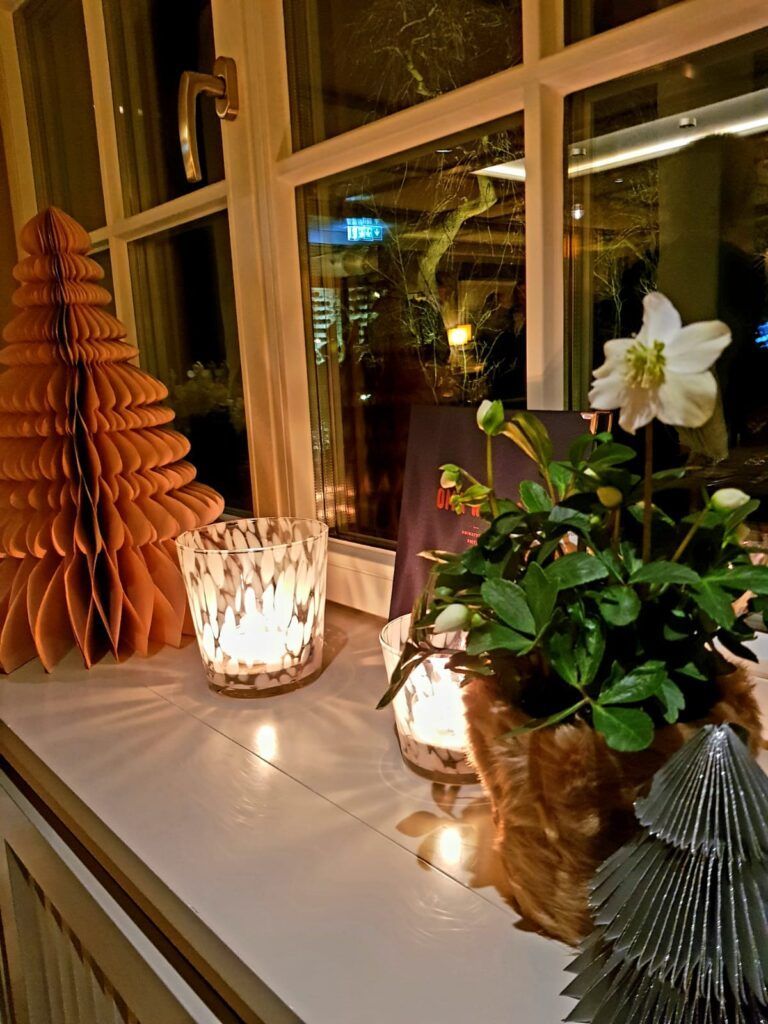 Ein Fensterbrett mit Kerzen und einem Weihnachtsbaum.