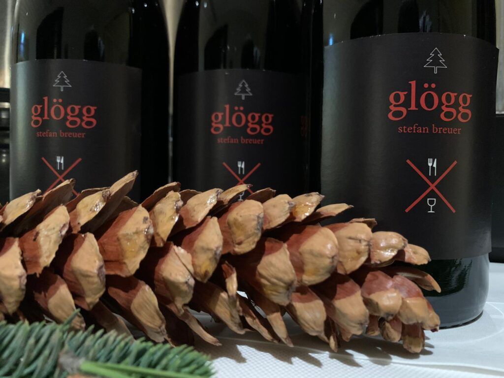 Drei Flaschen Glögg-Wein neben einem Tannenzapfen.