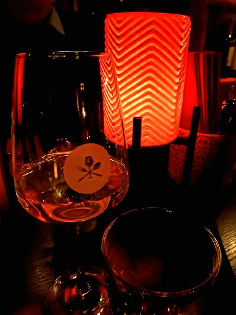 Ein Glas Wein auf einem Tisch neben einer Kerze.