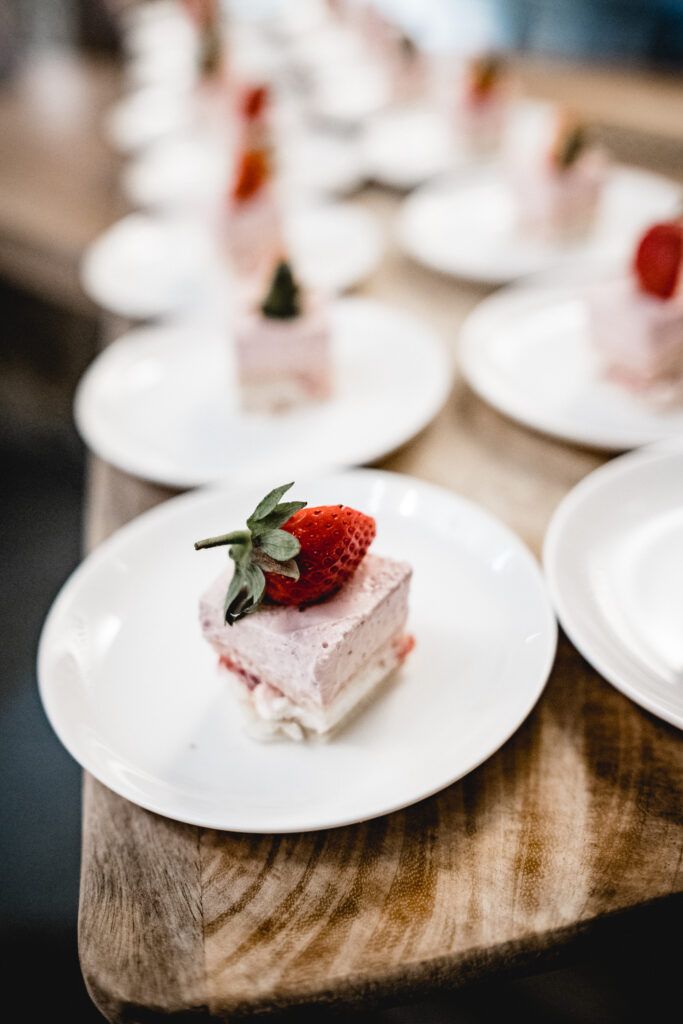 Erdbeerdesserts auf weißen Tellern auf einem Holztisch.