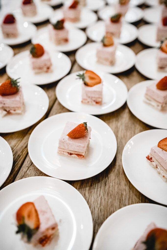 Erdbeerdesserts auf weißen Tellern auf einem Holztisch.