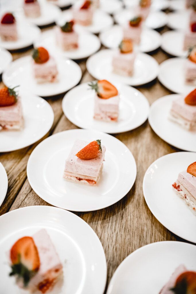 Erdbeeren und Sahnedesserts auf weißen Tellern.