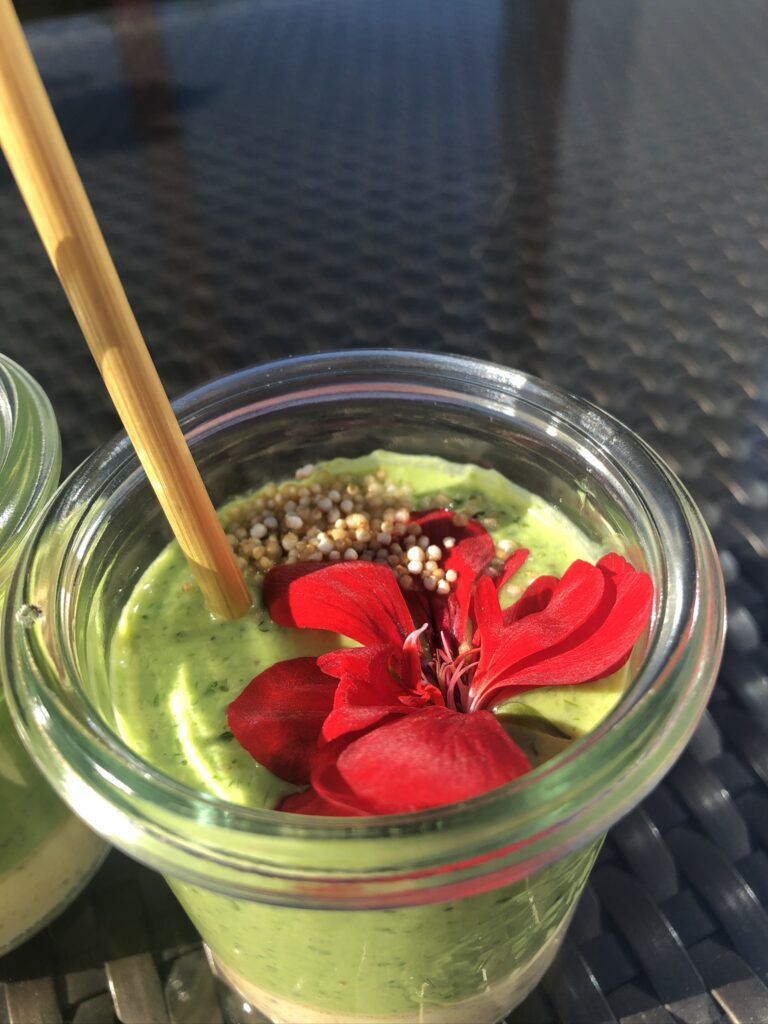 Zwei Gläser grüner Smoothie mit einer Blume darauf.