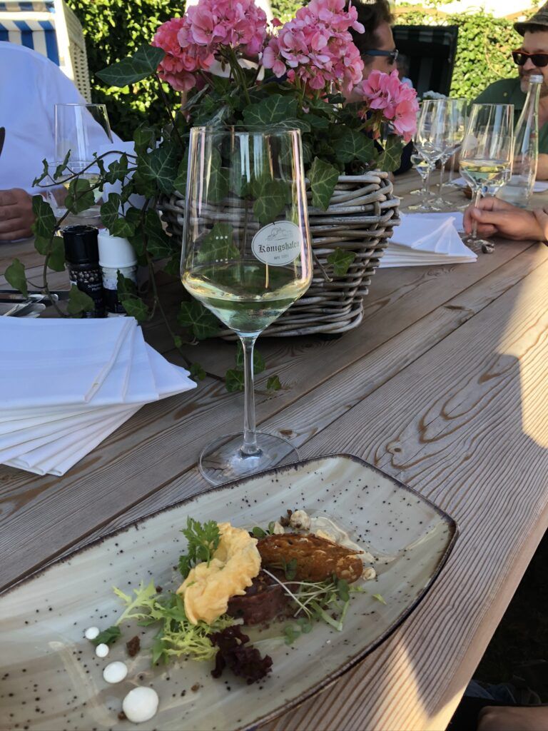 Ein weißer Teller mit Salat und einem Glas Wein.