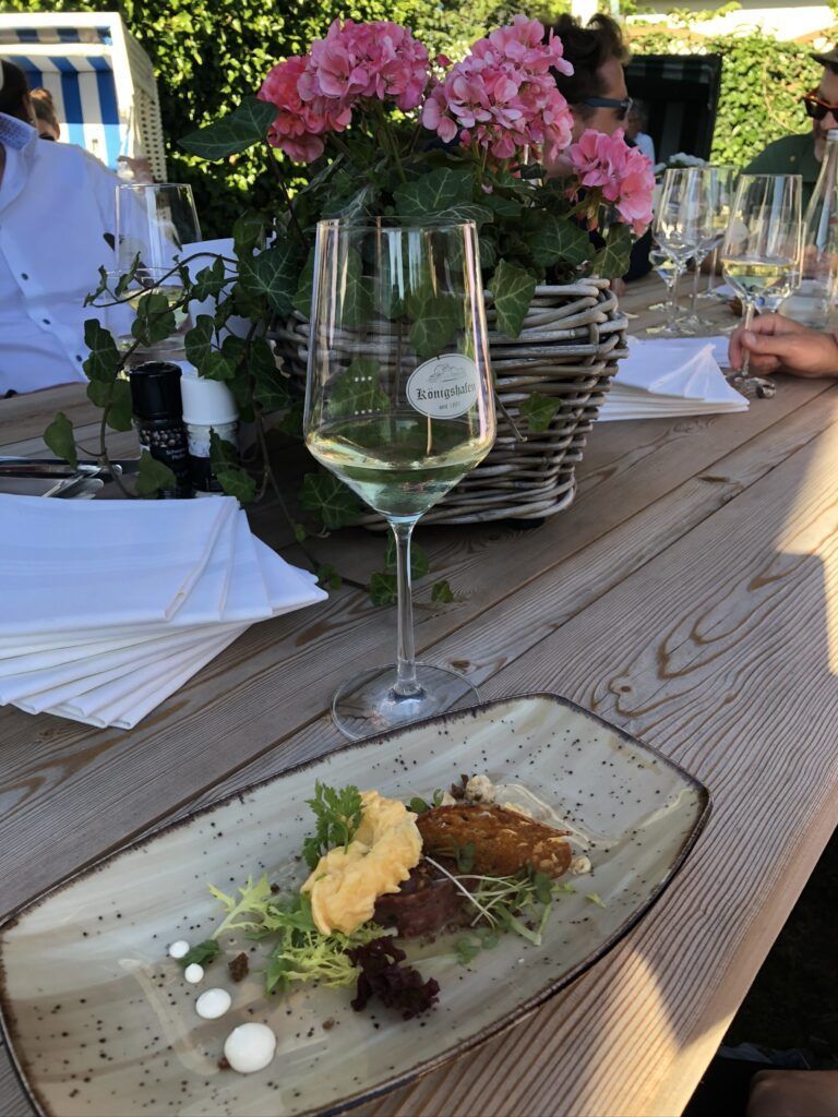 Ein Holztisch mit einem Glas Wein und einem Teller mit Essen.