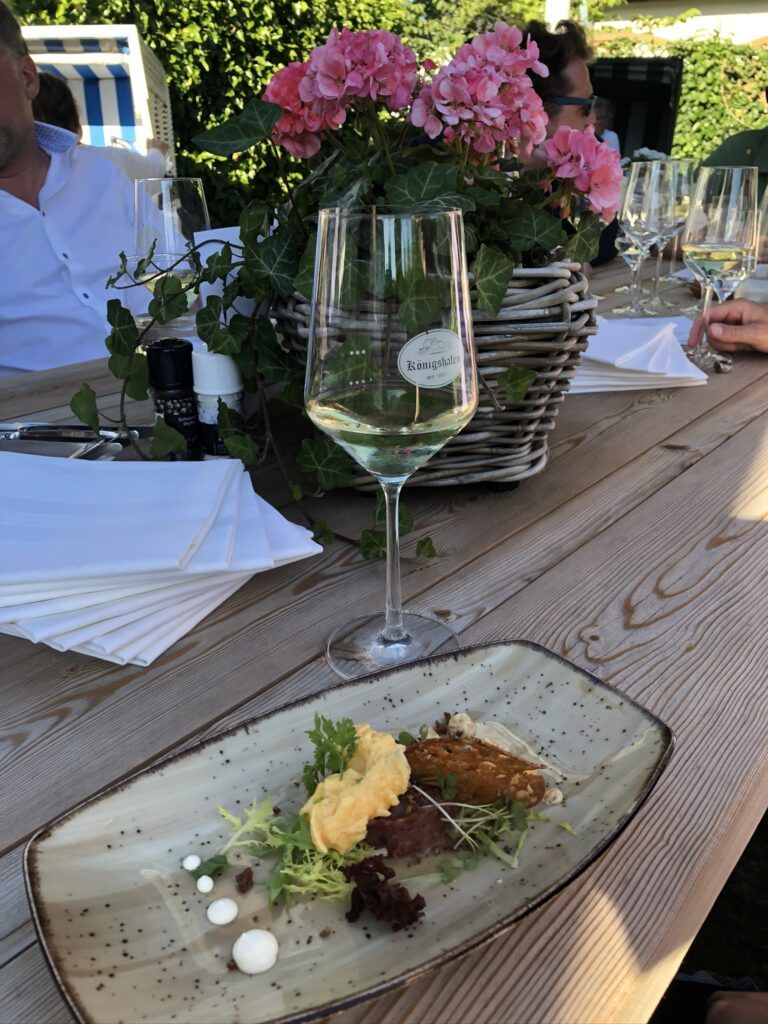 Ein weißer Teller mit Salat und einem Glas Wein.