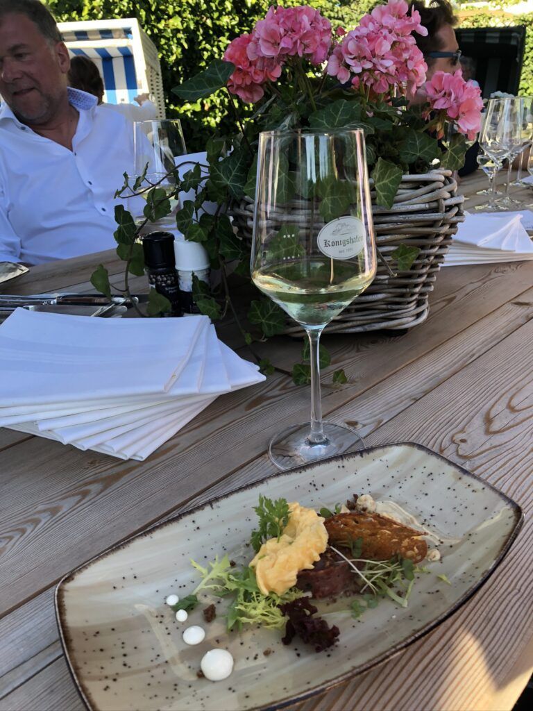 Ein Holztisch mit einem Teller mit Essen und einem Glas Wein.