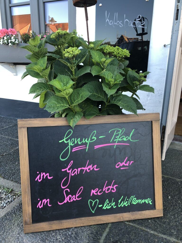 Eine Tafel vor einem Restaurant mit einer Pflanze darin.