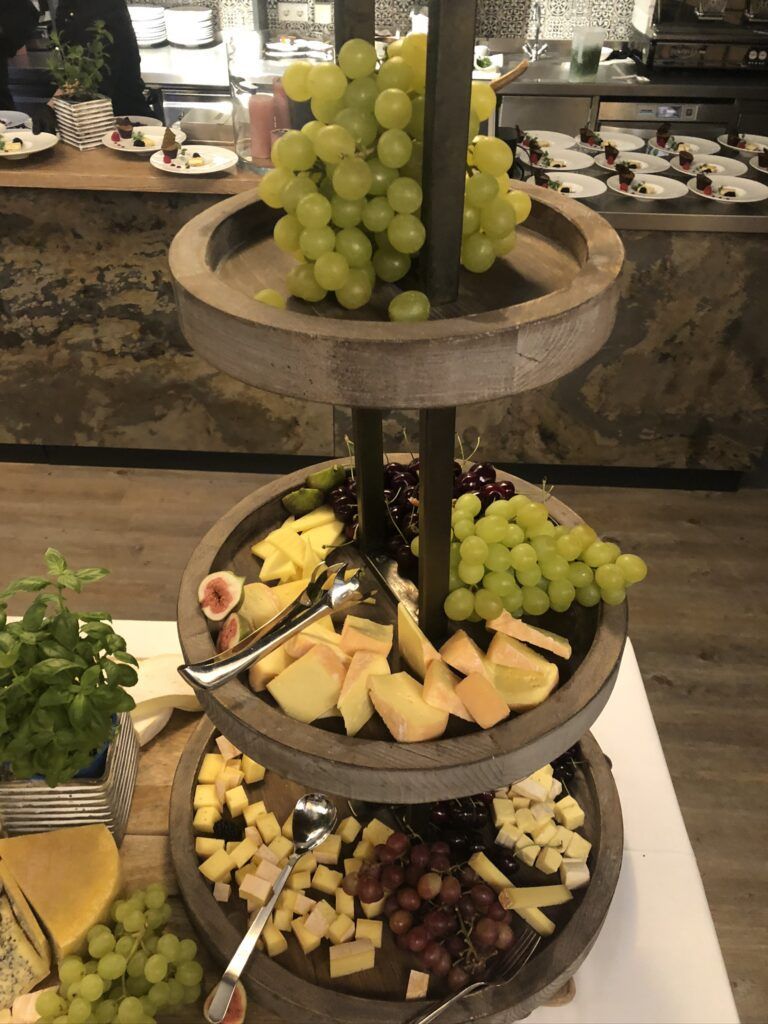 Drei Ebenen Obst und Käse auf einem Tisch.