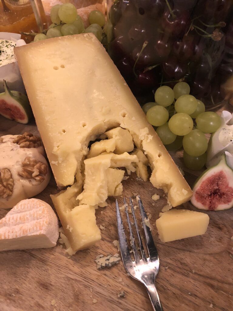 Ein Teller mit Käse, Trauben, Nüssen und einer Gabel.
