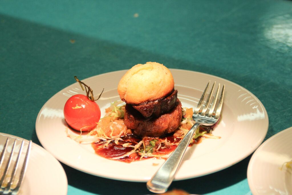 Ein Teller mit einem Burger auf einem Tisch mit Gabel.