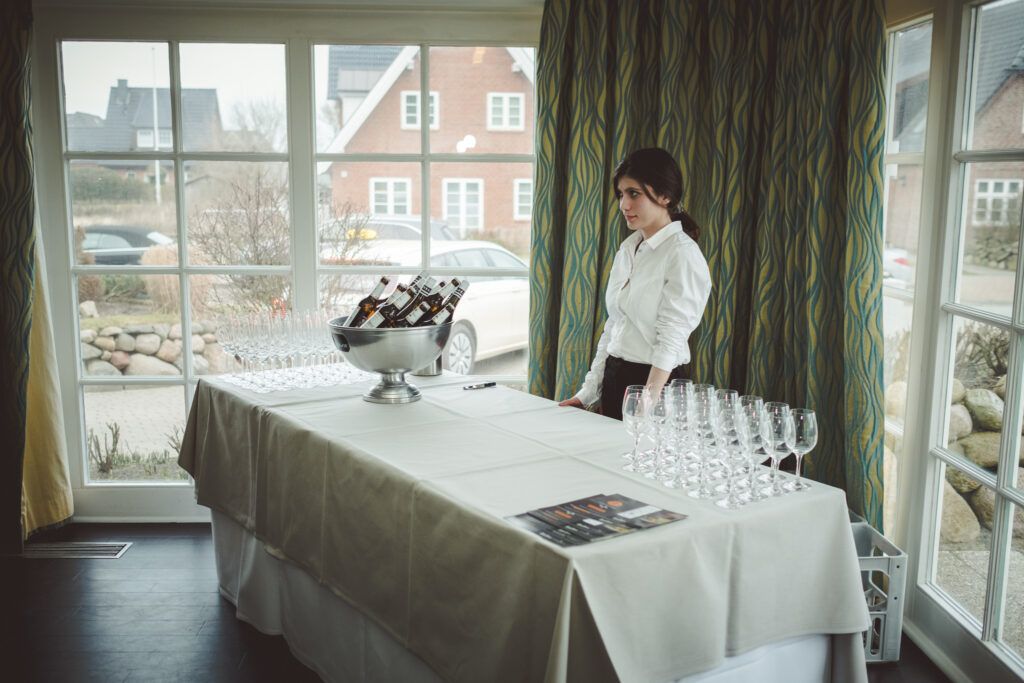Eine Frau steht mit Weingläsern vor einem Tisch.