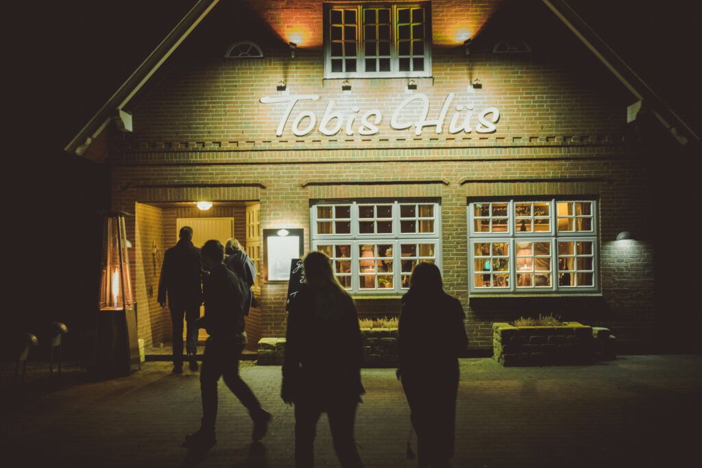 Eine Gruppe von Menschen steht nachts vor einem Restaurant.