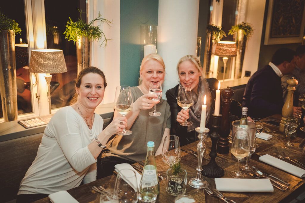 Drei Frauen halten Weingläser an einem Tisch in einem Restaurant.