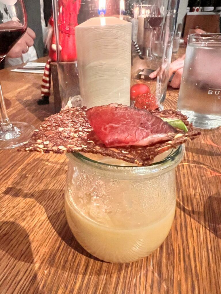 Ein Getränk mit einem Stück Fleisch darin auf einem Holztisch.