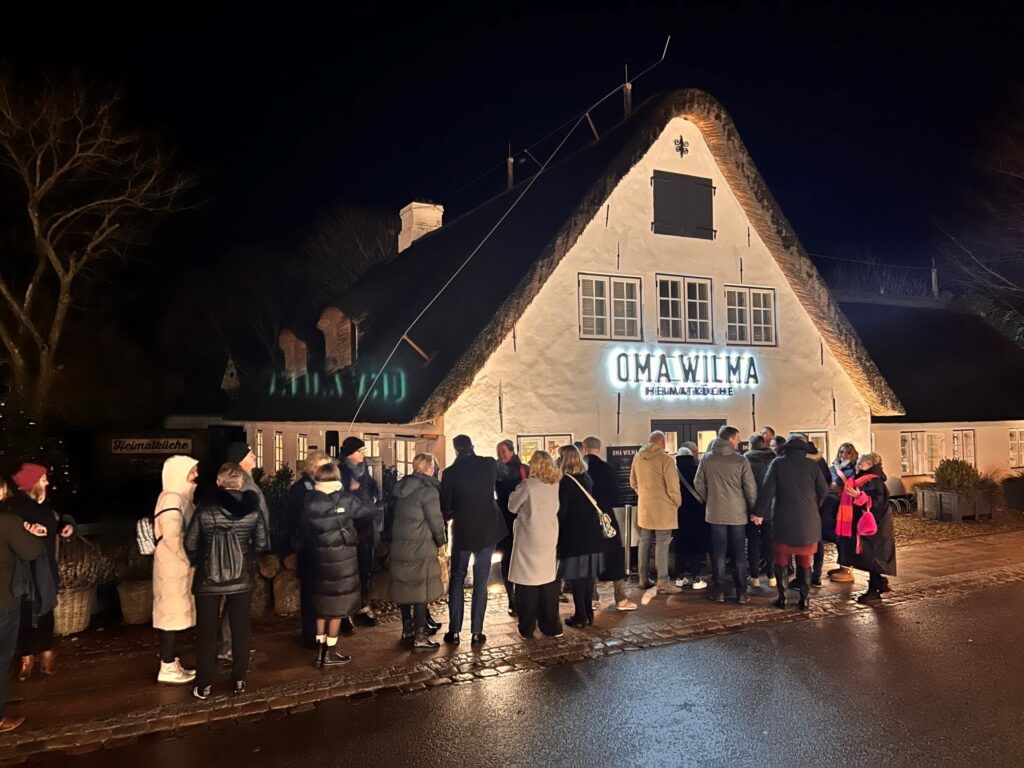 Eine Gruppe von Menschen steht nachts vor einem Haus.